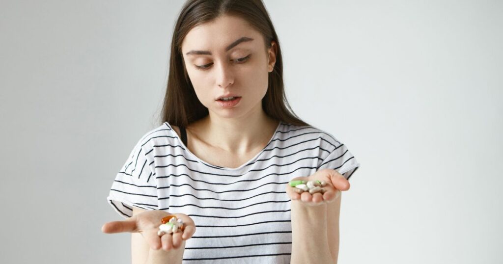 mulher olhando para uma caixa de antibiótico com expressão de dúvida